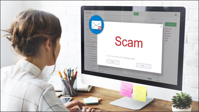 Uma mulher abrindo um e-mail em seu computador que diz "Scam".