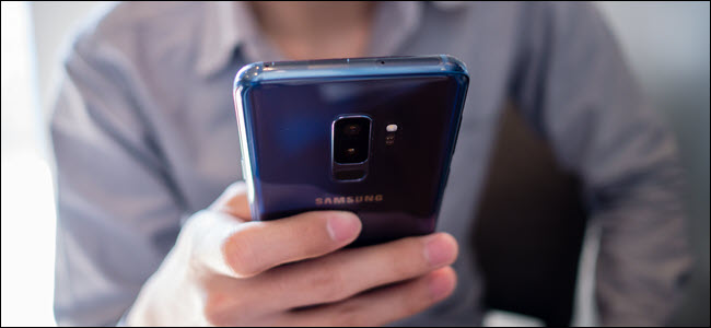 homem vestindo camisa cinza usa Samsung S9 plus azul