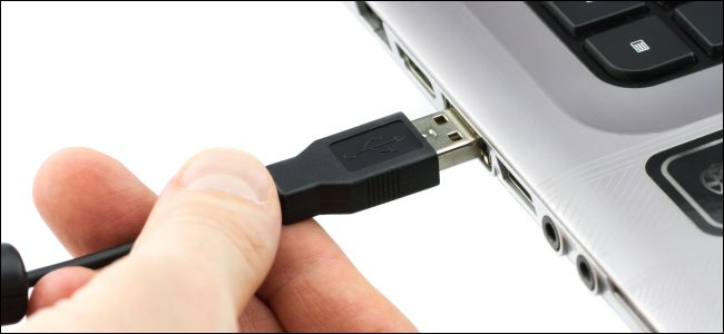 Uma mão conectando um cabo USB tipo A a um laptop.