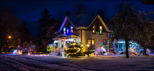 Casa particular coberta de neve com brilhantes luzes e decorações de Natal