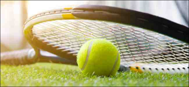 Bola e raquete de tênis na quadra de grama