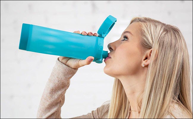 Uma mulher bebendo de uma garrafa de água inteligente.