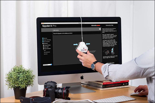 Uma ferramenta de calibração de monitor Datacolor SpyderX Pro pendurada na frente de um monitor de computador.