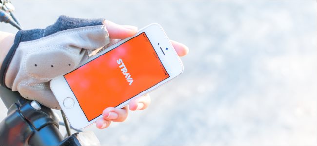 Uma pessoa segurando um smartphone com o aplicativo Strava enquanto anda de bicicleta.