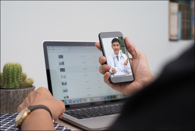 Um homem se comunicando com um médico por meio de bate-papo por vídeo em um smartphone.