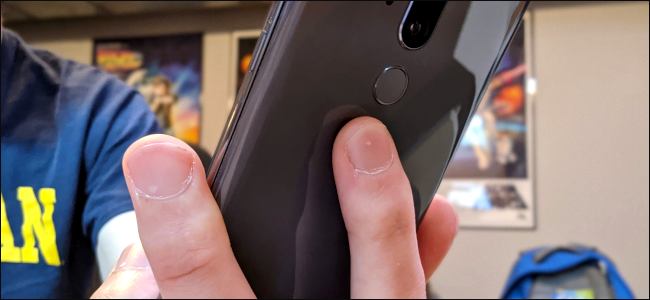 Os dedos de alguém na parte de trás de um telefone Android.