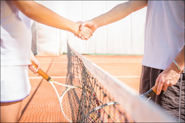 Dois jogadores apertando as mãos em uma quadra de tênis