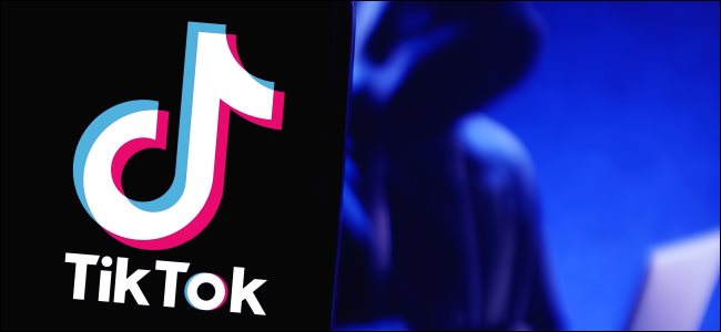 Um logotipo da TikTok em um telefone com uma figura usando um laptop ao fundo.