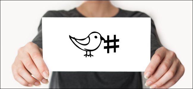 Alguém segurando um cartão com o pássaro do Twitter desenhado ao lado de uma hashtag.