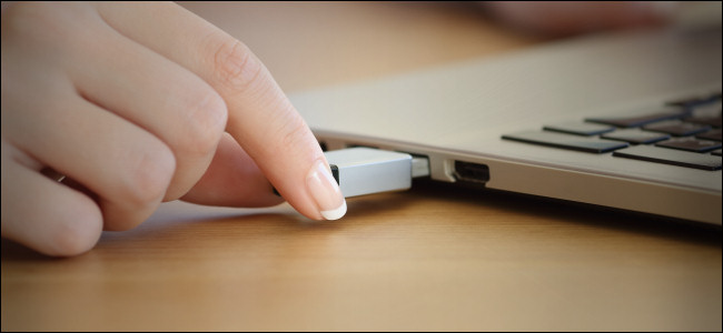 Uma mulher conectando uma unidade USB em um laptop.