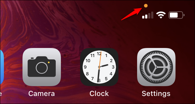 O círculo laranja acima do indicador de celular em um iPhone.