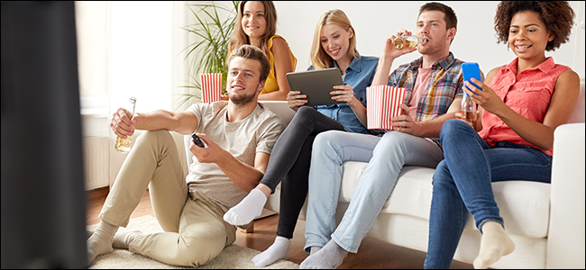 Um grupo de amigos assiste Netflix em um sofá.