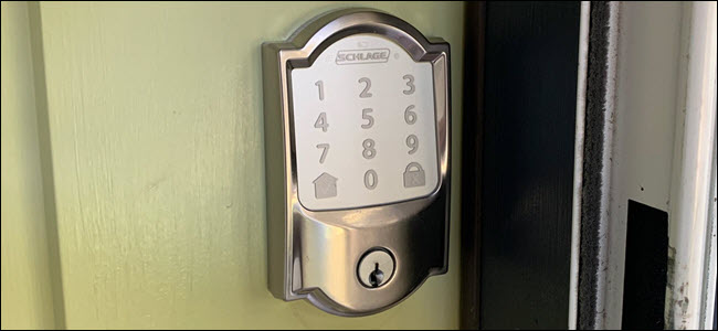 Um smartlock Schlage Encode estilo cetim instalado em uma porta verde.