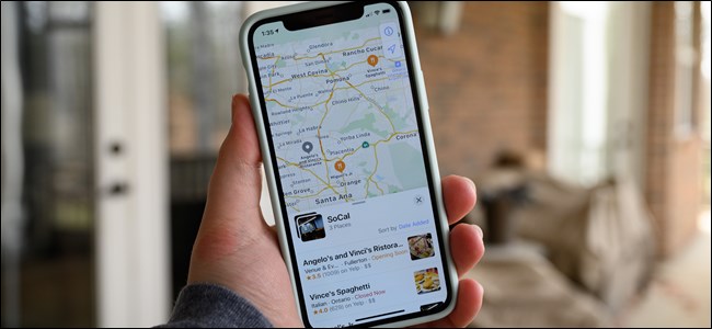 Uma mão segurando um iPhone com uma coleção de mapas da Apple na tela.