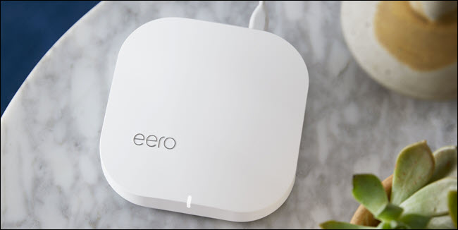 Um roteador eero Wi-Fi em uma mesa ao lado de uma planta.