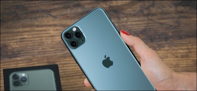 Uma mão segurando um iPhone 11 Max Pro e mostrando a parte de trás com a câmera.