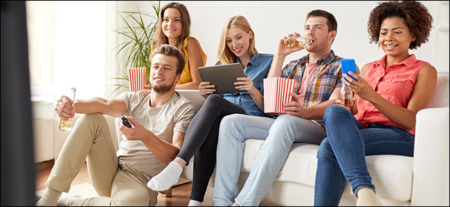 Um grupo de amigos comendo pipoca e assistindo TV.