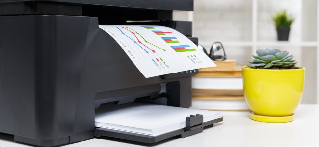 Uma impressora sentada em uma mesa, imprimindo uma folha de papel com um gráfico de barras.