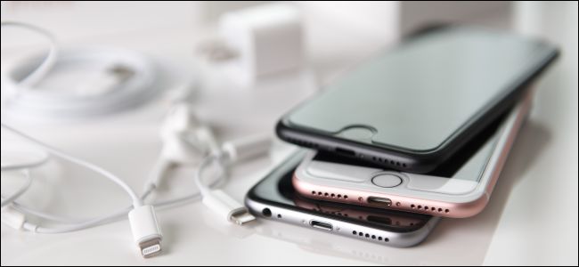 IPhones antigos empilhados uns sobre os outros, próximos a fios de luz.