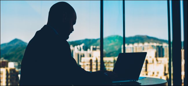 A silhueta de um homem navegando em um laptop.