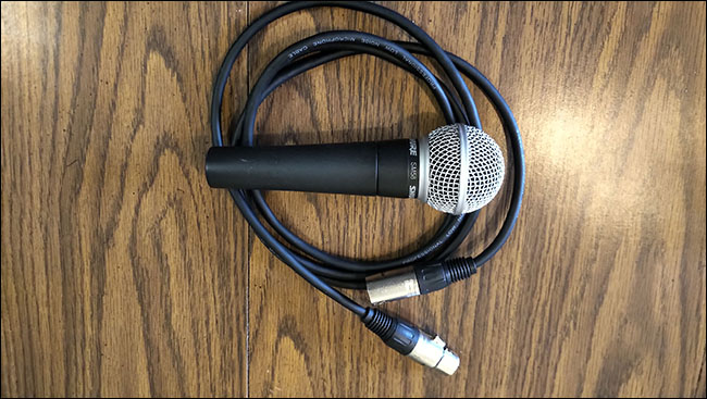 Um microfone Shure SM58 em cima de um cabo XLR da AmazonBasics em uma mesa.