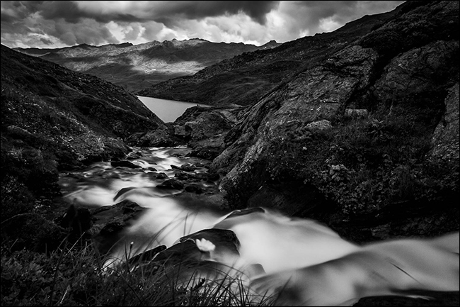 Uma foto em preto e branco de um riacho nas montanhas depois de chover.