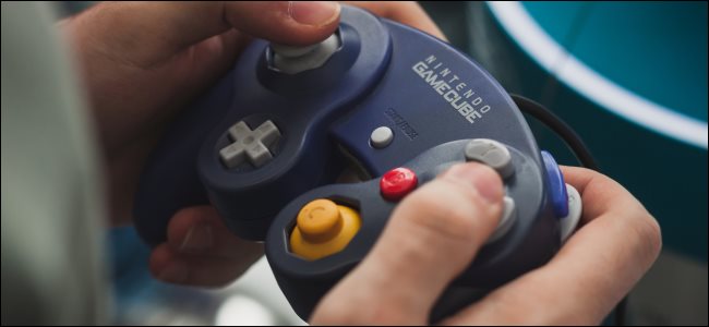 Mãos segurando um controlador Nintendo GameCube.