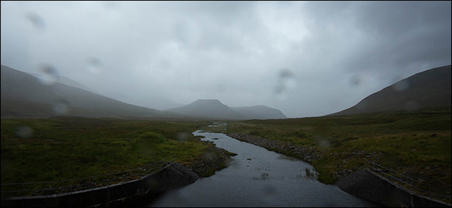 Uma montanha e um riacho em um dia nublado e chuvoso.