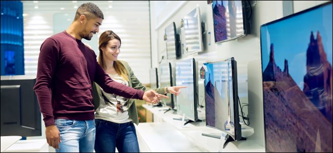 Um casal comprando TVs em uma loja.