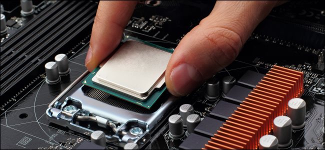 Uma mão conectando uma CPU em um soquete na placa-mãe.