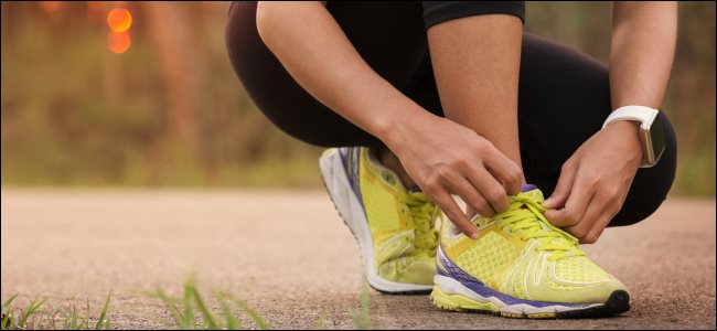 Uma pessoa amarrando os sapatos antes de uma corrida usando um relógio inteligente.