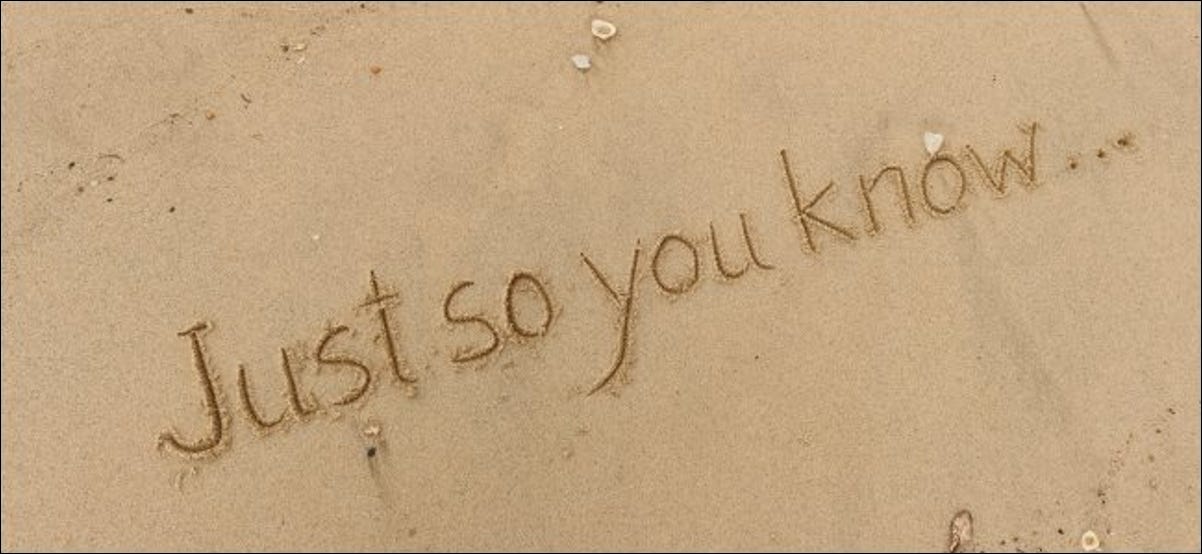 As palavras "Just So You Know" escritas na areia de uma praia.