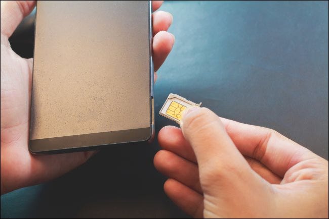 Uma mão inserindo um cartão SIM em um smartphone.