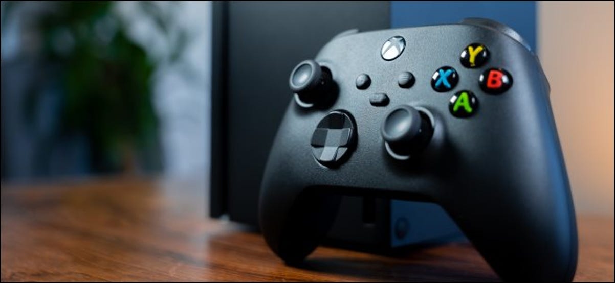 Um controlador de Xbox com um Xbox Series X em segundo plano