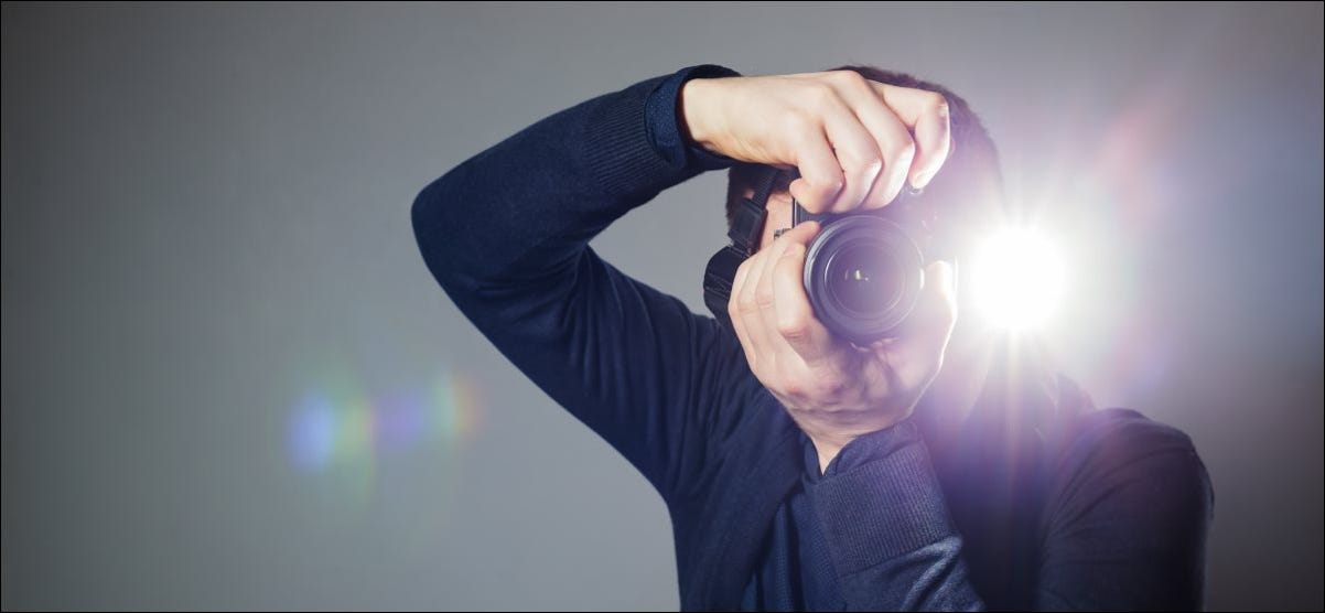 Um homem tira uma foto com uma câmera com flash embutido.