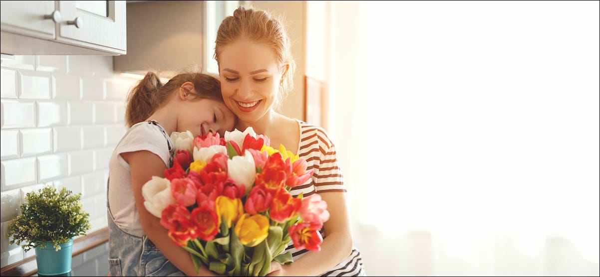 Mãe e filha segurando flores e comemorando o Dia das Mães