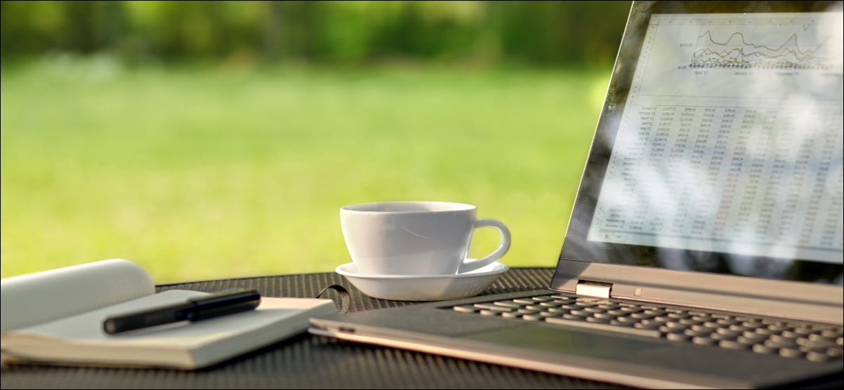 Um laptop sentado em uma mesa do lado de fora em um dia ensolarado.