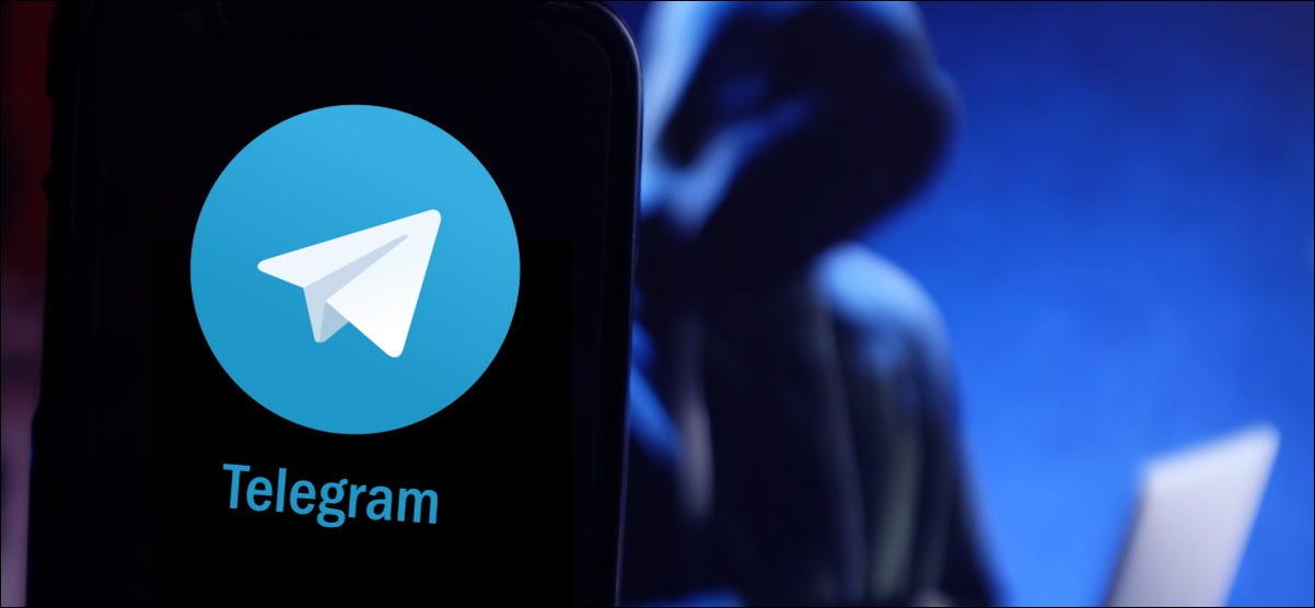 Uma figura sombria em um laptop atrás de um smartphone com o logotipo do Telegram.