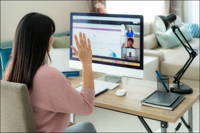 Uma mulher acenando para um computador durante uma videochamada.