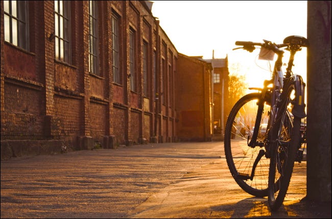 Uma bicicleta estacionada na calçada da cidade ao pôr do sol.