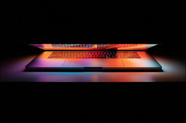 Um Apple MacBook Pro parcialmente fechado e brilhando no escuro.