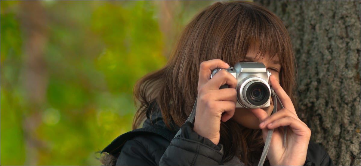 Uma pessoa tirando fotos com uma câmera compacta.