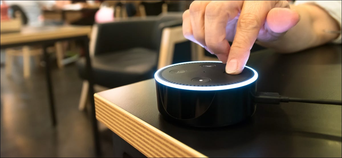 Um dedo pressionando um botão em um Amazon Echo Dot em uma cafeteria.