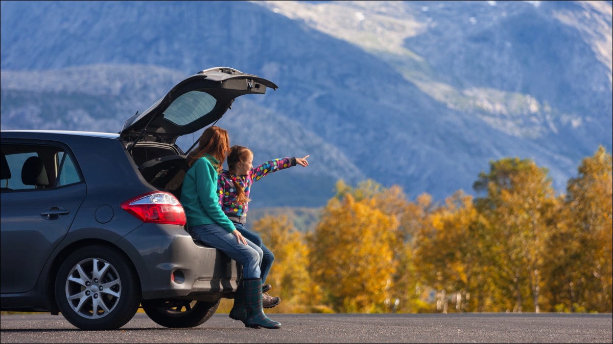 Turistas olhando para uma montanha da parte de trás de seus carros.