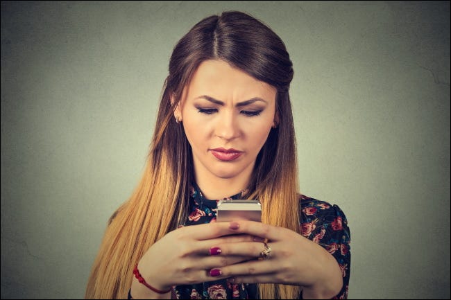 Uma mulher infeliz olhando para um smartphone.
