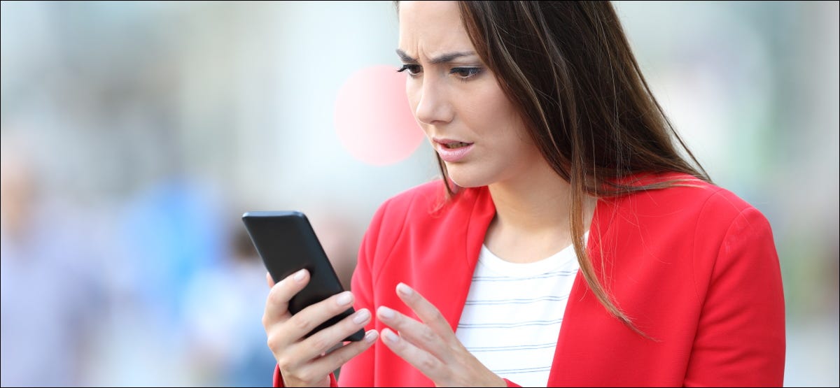 Uma mulher preocupada olhando para seu smartphone.