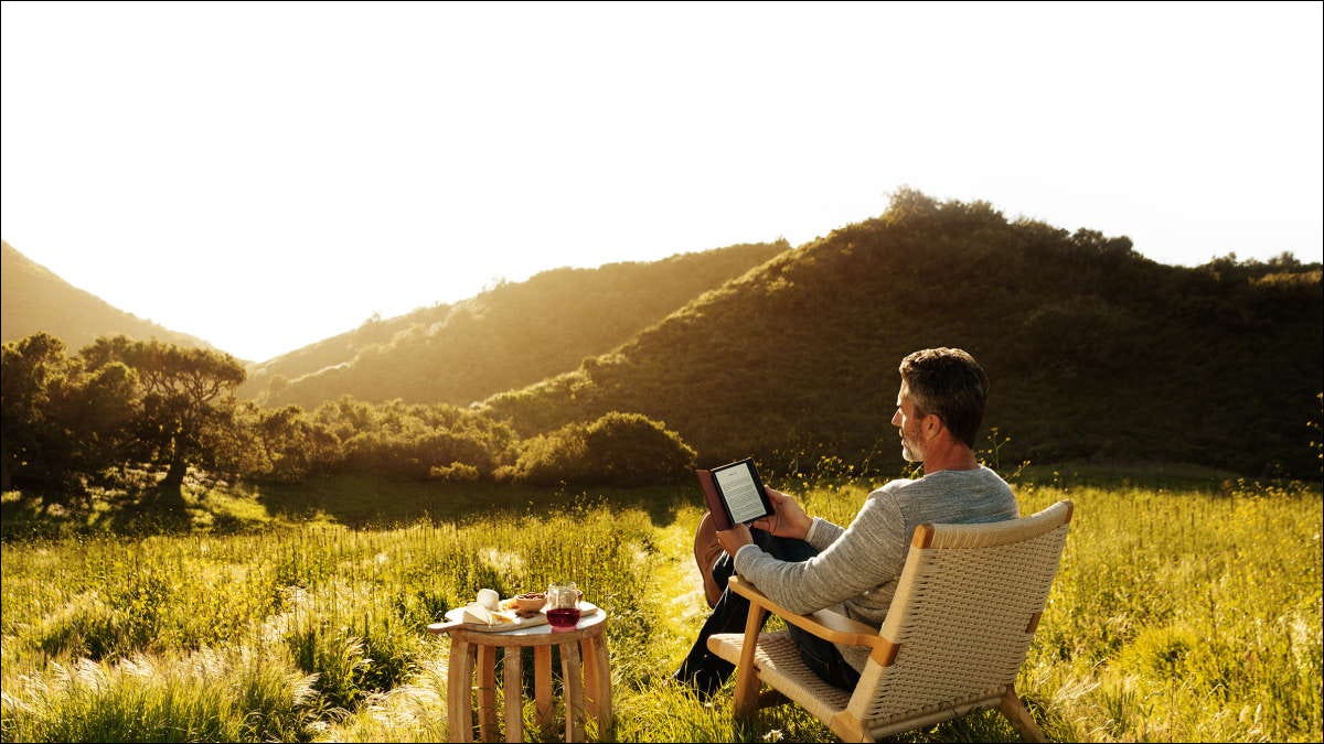 homem lendo kindle lá fora em paisagem montanhosa