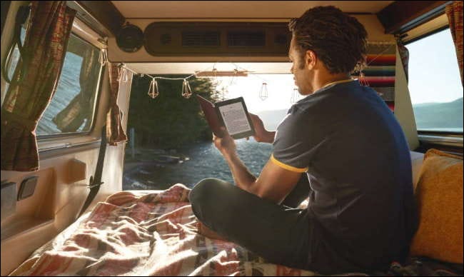 homem lendo kindle no banco de trás da van