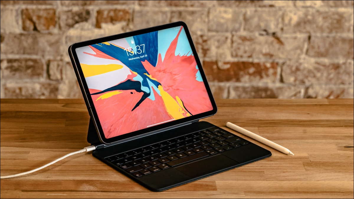 iPad com capa de teclado e caneta na mesa de madeira