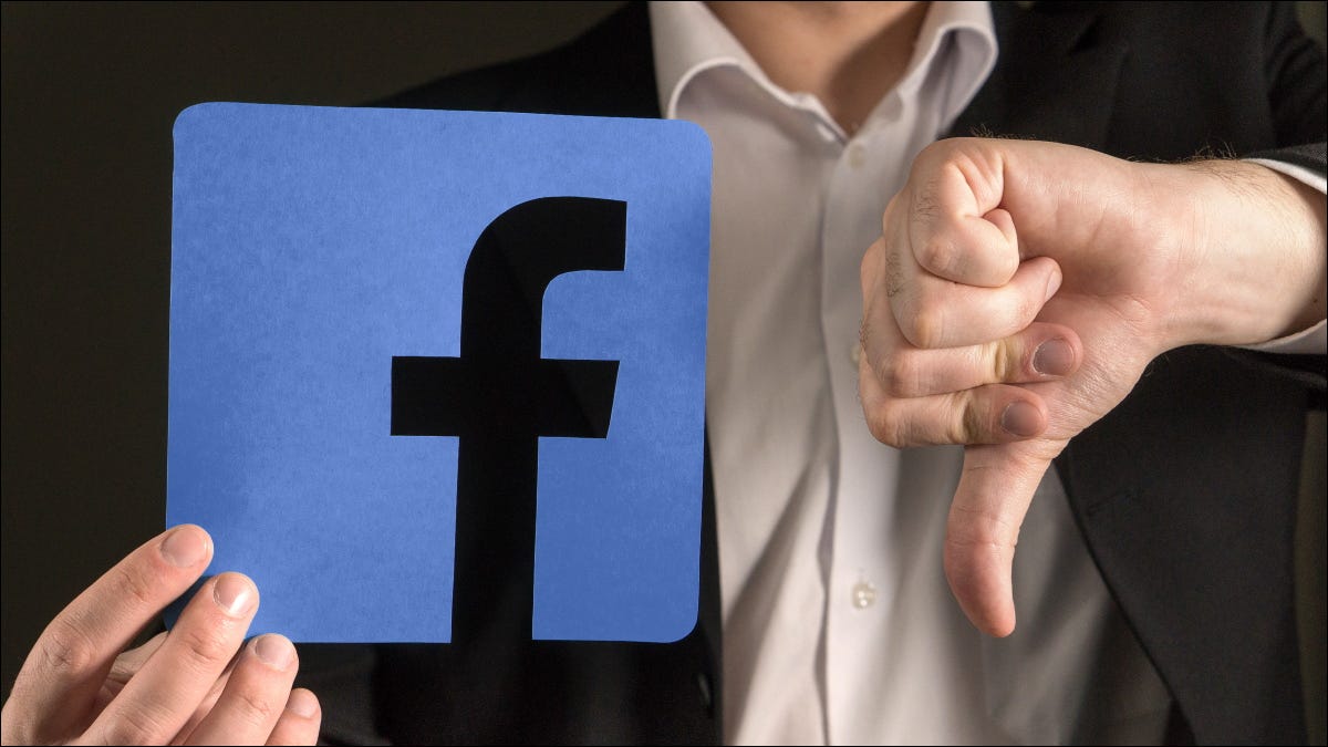 Um homem dando um polegar para baixo para um logotipo do Facebook.